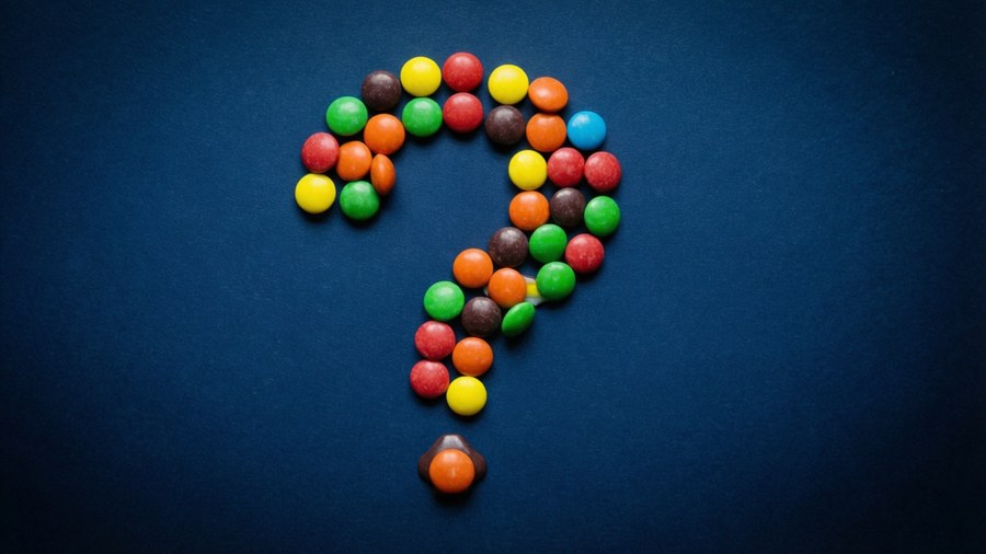 Smarties che formano un punto interrogativo su blu scuro, misterioso.