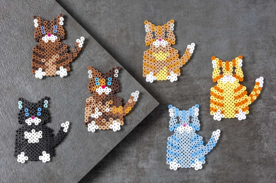Ensamling af katteformede perler på en grå overflade.
