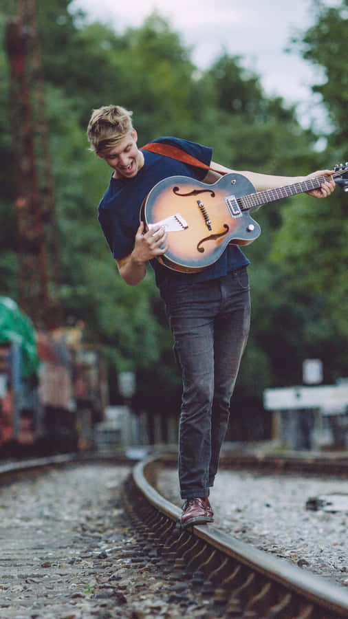 GeorgeEzra George Ezra is an English singer-songwriter and musician. His music is a unique blend of folk, pop, and rock. He rose to fame with his hit single "Budapest" and has since released multiple successful albums. George Ezra's soulful voice and heartfelt lyrics make him a beloved artist in the music industry. If you're a fan of George Ezra, you can show your support by downloading his wallpapers for your computer or mobile devices. These wallpapers feature stunning images of George Ezra, capturing his essence and talent. With these wallpapers, you can have a constant reminder of your favorite artist as you go about your day. So don't miss out on the opportunity to personalize your devices with George Ezra wallpapers. Download them now and let his music stay with you wherever you go.