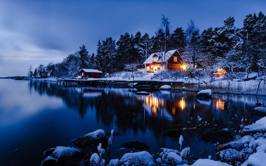 Winter landscape with a house on the lake shore during a holiday eve.