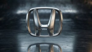 Logo Honda metalik 3D mengambang di permukaan reflektif