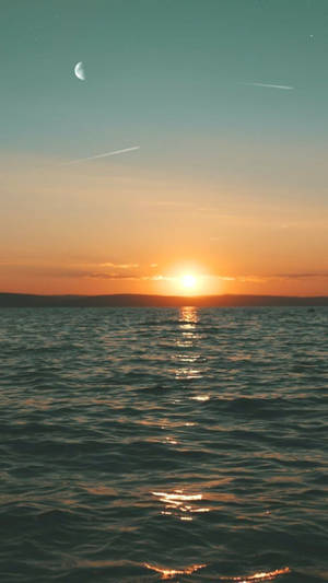 Sunset over ocean with moon and airplane trails in sky — Android Picture