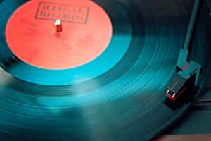 Disco de vinilo verde azulado girando en un tocadiscos con etiqueta roja y brazo del tocadiscos visible. — 80S Fondos de pantalla