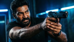 Vijay in an intense action pose aiming a gun with neon lights.