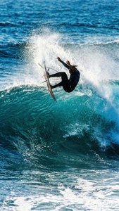 Seorang peselancar terbang di atas ombak miring dalam trik udara.