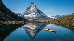 Sebuah kayak di danau alpen murni yang memantulkan puncak gunung bersalju dengan sempurna.