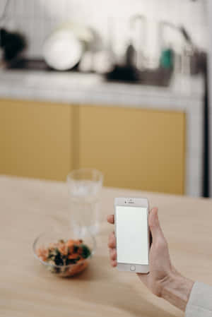 Hand holding phone over salad and water on kitchen table — Kitchen Wallpaper