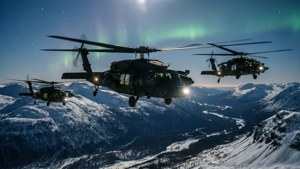 MH-60M Black Hawk formation over snowy mountains at night with aurora
