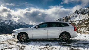 Volvo V90 Cross Country in het wit op besneeuwde bergpas, dramatische lucht