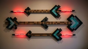 Tres flechas estilo Minecraft con luces LED rojas montadas en una pared.
