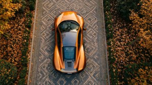 Top-down view of McLaren MP4-12C on a patterned driveway with autumn leaves.