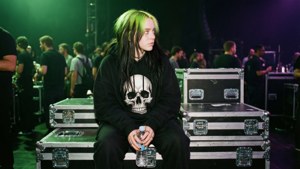 Billie Eilish backstage, doodshoofdhoodie, road cases, candid, groen-paars licht