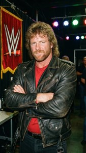WWE-bryter i skinnjakke står backstage med armene i kors.