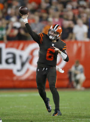 Cleveland Browns quarterback kastar en fotboll under en nattmatch.