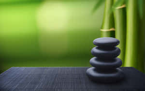 Stacked black zen stones on a bamboo mat with green bamboo in background