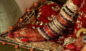 Bride's decorated hand with bangles on red fabric