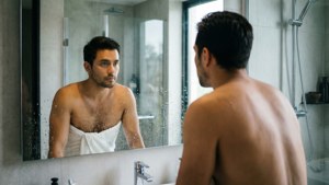 Mann frisch aus der Dusche bewundert sich selbst im Badezimmerspiegel.