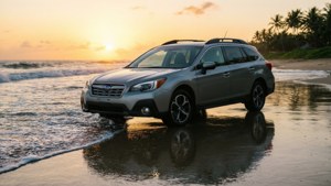 Subaru Outback an einem Strand bei Sonnenuntergang mit Palmen und Spiegelungen.