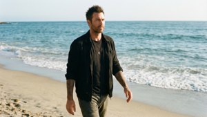 Adam Levine che cammina sulla spiaggia, casual e rilassato.