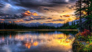 Pôr do sol sobre lago de montanha com reflexo da floresta e nuvens dramáticas — Lago Papéis de Parede