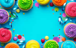 Cupcakes coloridos com granulados e fitas dispostos em uma borda festiva sobre azul. — Cupcake Papéis de Parede