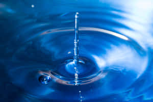 Una gota de agua suspendida sobre una superficie de agua azul creando ondas y reflejos. — One Piece Blue Fondos de pantalla