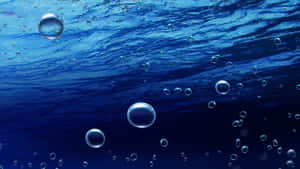 Blasen steigen in tiefblauem Wasser auf, mit sich kräuselnder Oberfläche darüber. — Blue Beach Aesthetic Wallpaper