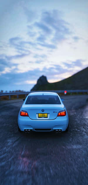 Light blue BMW car driving on wet mountain road at dusk. — Bmw M iPhone Picture