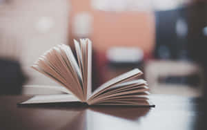 Open book with fanned pages on wooden table in soft warm light. — Books Background