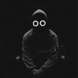 Eine vermummte Person mit leuchtenden Augen, die im Dunkeln eine Gitarre hält.