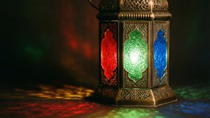 Close-up of a brass Islamic lantern with colored glass casting patterned light