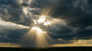 Auringonvalo puhkeaa myrskypilvien läpi, vertauskuva itseluottamuksen esiin nousemiselle.