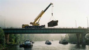 Sebuah derek bergerak memasang bagian jembatan di atas sungai berkabut.