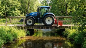 Uno sfondo naturale luminoso di un trattore New Holland che attraversa un ponte di legno con riflessi del ruscello