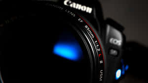 Close-up of a Canon camera lens with blue light glow. — Camera Wallpaper