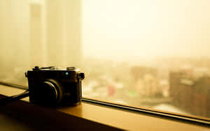 Vintage camera on windowsill with blurred city view in golden light — Camera Wallpaper