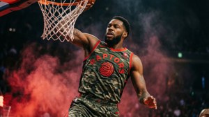 Basketball player in camouflage Raptors jersey dunking with red smoke behind him. — Lou williams Picture