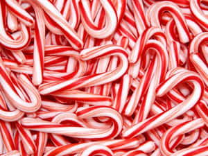 A pile of red and white striped candy canes for holiday use. — Candy Cane Wallpaper