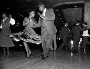 Couples dancing in a 1950s nightclub with swirling skirts and suits.