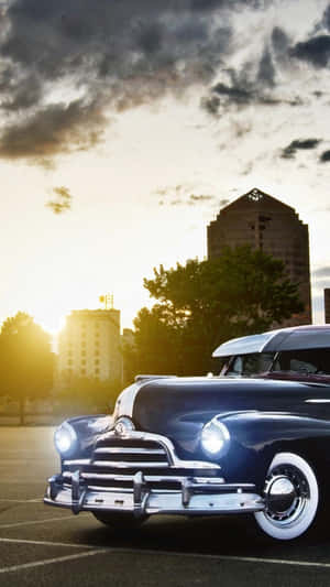 Classic blue car with chrome details parked in city lot at sunset. — Old Car Wallpaper