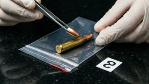 Forensisch technicus verzamelt hulzen met pincet in verzegelde zak