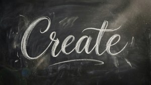 Un fond d'écran créatif avec 'Create' en calligraphie à la craie blanche sur un fond réaliste de tableau noir.