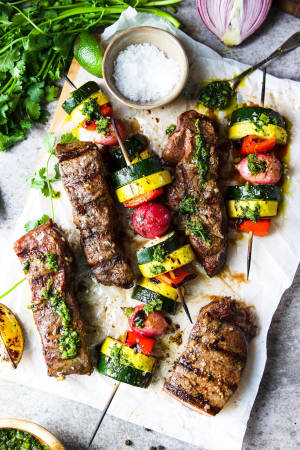 Grillade biff- och grönsaksspett med örtsås och färska garneringar på bakplåtspapper. — Churrasco Bakgrundsbilder