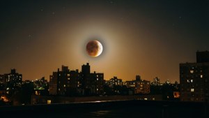 Gerhana bulan perkotaan dengan bulan yang sebagian tertutup di atas gedung-gedung kota
