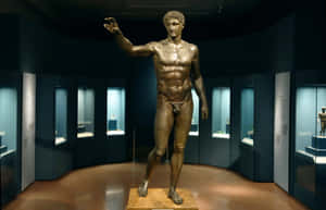 Bronze statue of a muscular man in a museum gallery with display cases. — Classical Music Picture