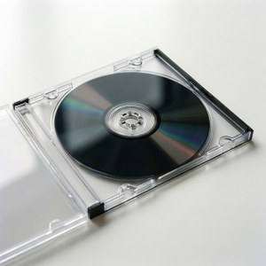 Un boîtier DVD transparent avec un disque noir à l'intérieur sur une surface blanche, photo produit minimaliste.