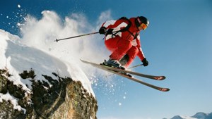 Skier jumping off cliff into powder