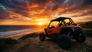 En oransje buggy silhuettert på en klippe ved solnedgang med brennende skyer.