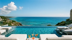 Vista lujosa de resort de verano con piscina infinita y horizonte oceánico.