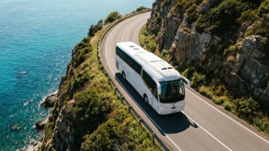 Et ovenfra-ned-blikk av en Irizar i8-buss på en svingende kystklippevei med turkis hav